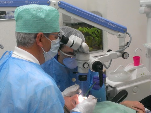 doctor en sesión de implantología usando microscopio